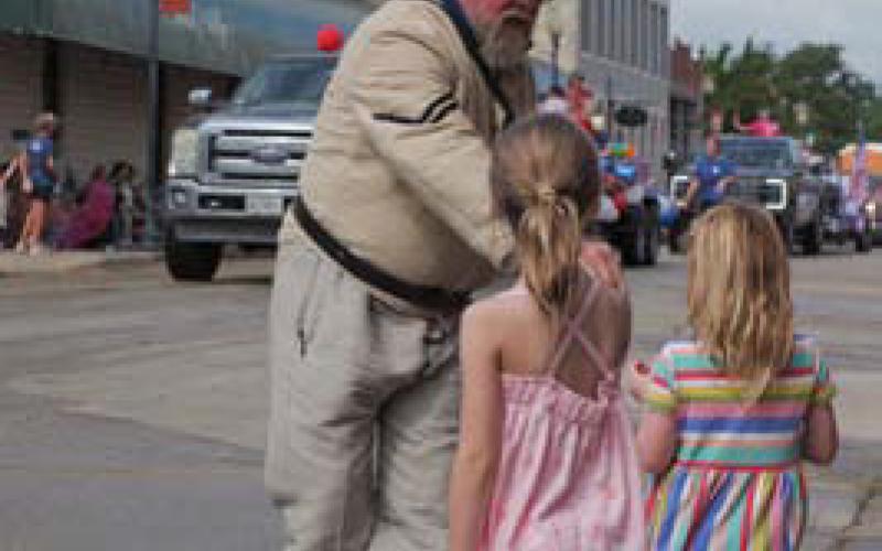 A Spring Ho Grand Parade participant hands a treat to a pair of children during Saturday’s event. ADAM BARRIOS | DISPATCH RECORD
