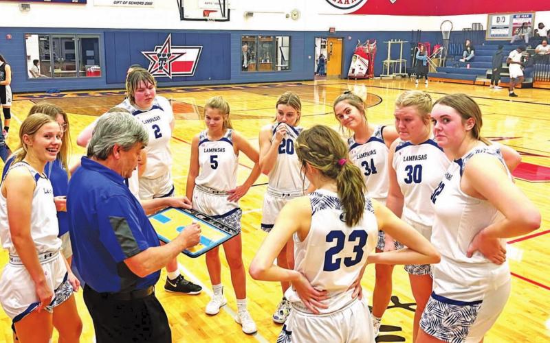 Head coach Mark Myers speaks to his team in the huddle while they are up late in a tournament game, and a few girls strike a pose for the camera. COURTESY PHOTO