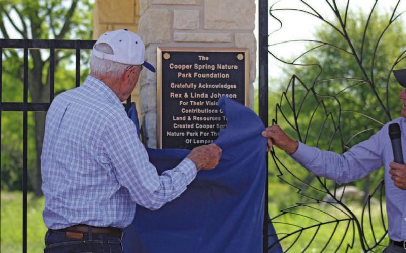 Rex Johnson, assisted by Harrell Clary at right, unveils the plaque dedicating Cooper Spring Nature Park and recognizing Johnson and his wife, the late Linda Johnson, for their work and generosity in making the park a reality. JOYCESARAH MCCABE | DISPATCH RECORD