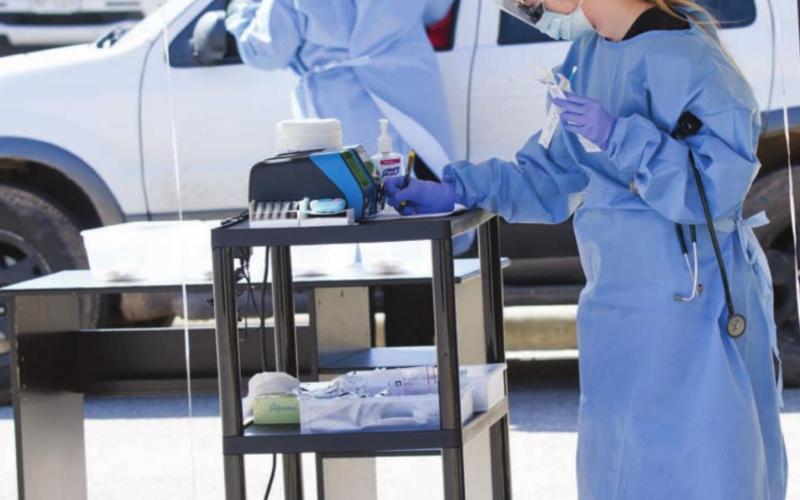 Family Nurse Practitioners Elizabeth Smith, in foreground, and Amanda Allen, in background, run COVID-19 tests for patients outside Family Medicine Clinic in March. FILE PHOTO