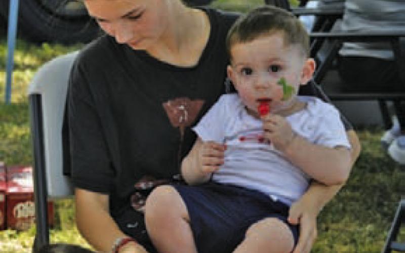 Zodee Gorecki holds onto Dyce Earle who enjoys a lollipop during a face-painting session. ERICK MITCHELL | DISPATCH RECORD