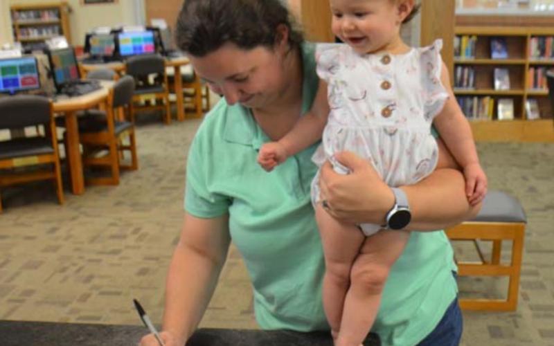 Nicole Baker of Lampasas signs up her 1-year-old daughter Millie on Tuesday at the Lampasas Public Library to participate in Dolly Parton’s Imagination Library program. MONIQUE BRAND | DISPATCH RECORD