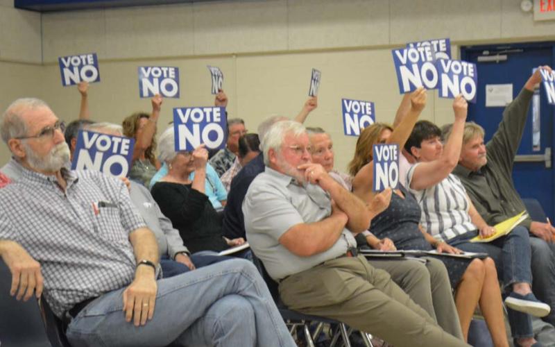Audience members hold signs in opposition to tax incentives for a solar farm project under consideration by the Lampasas Independent School District. MONIQUE BRAND | DISPATCH RECORD
