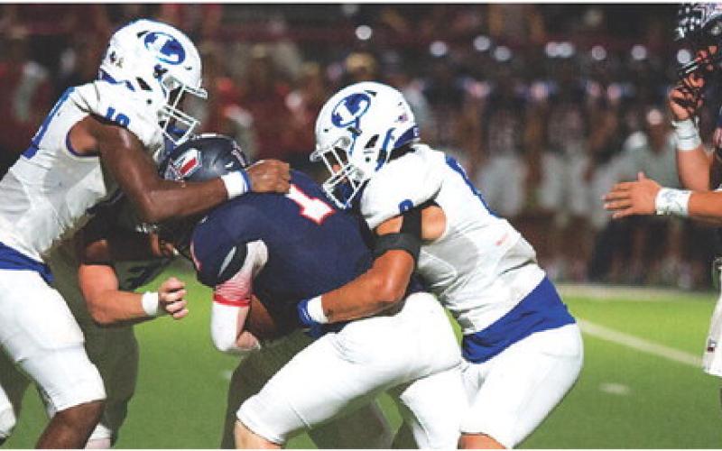 Trenton Hobbs, left, and Eli Calderon wrangle the ball carrier. HUNTER KING | DISPATCH RECORD