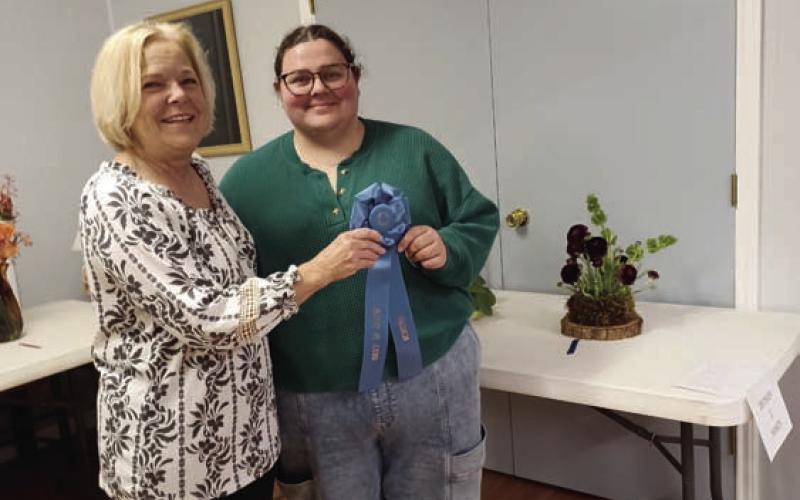 Holly Hines, at right, garnered the Best in Show Award for her arrangement using dark-purple ranunculus. Sheri Stone presented the award on behalf of the L-M Garden and Civic Club. COURTESY PHOT0