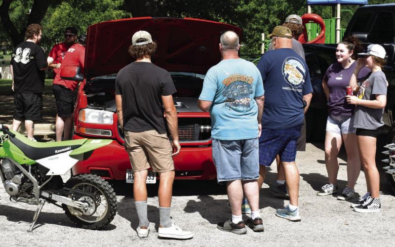 Sulphur Creek Car Cruise attendees take interest in one of the many vehicles on display on Saturday. JOSEPH NEUENSCHWANDER | DISPATCH RECORD