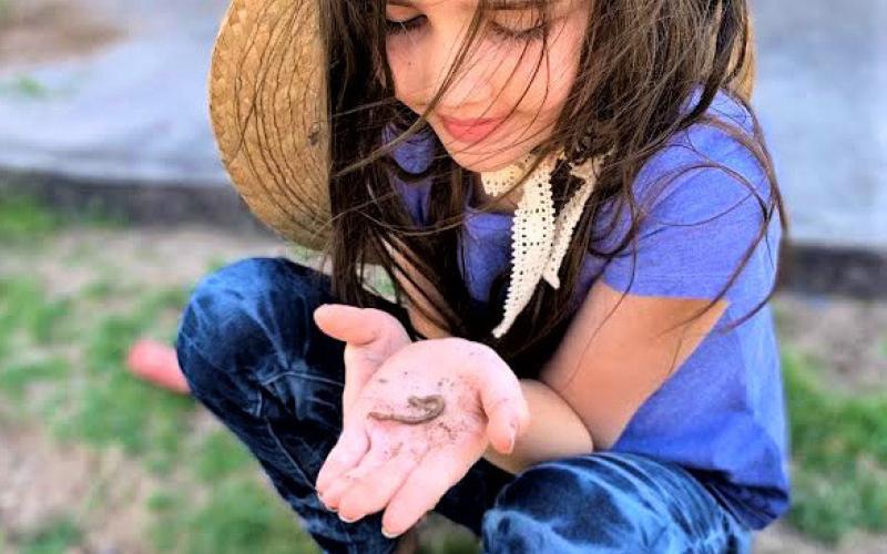 Cecily Hatley, age 8, sets an example of wonder and enjoyment as she examines and appreciates an earthworm found in her mother’s flower garden. Joycesarah McCabe | Dispatch Record