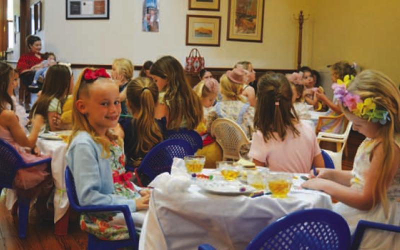At left, Reagan Groves gives the camera a smile while her fellow Teddy Bear Tea Party attendees stay locked into storytime. ERICK MITCHELL | DISPATCH RECORD