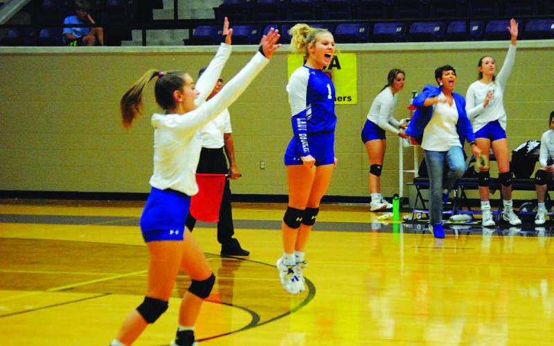 Kayli Syx, left, and Bre Quarles celebrate a point during the playoff matchup. Head coach Christy Wiley and the bench also show their excitement. HUNTER KING | DISPATCH RECORD