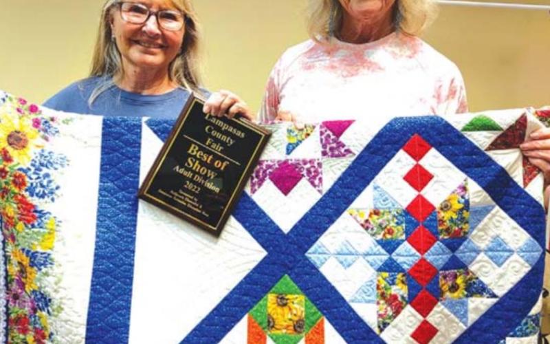 Best of Show winner Naomi Schroyer, at left, displays her winning quilt entry, with assistance from Cathy Allen of the ‘36 Club. MASON HINES | DISPATCH RECORD