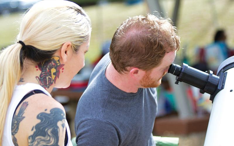 hunter king | DISPATCH RECORD Allan Straub looks through his telescope during late morning Monday before the full eclipse was in effect. He and Jenna Herrington, left, ventured up from the Austin area to view the astronomical event in Lampasas.