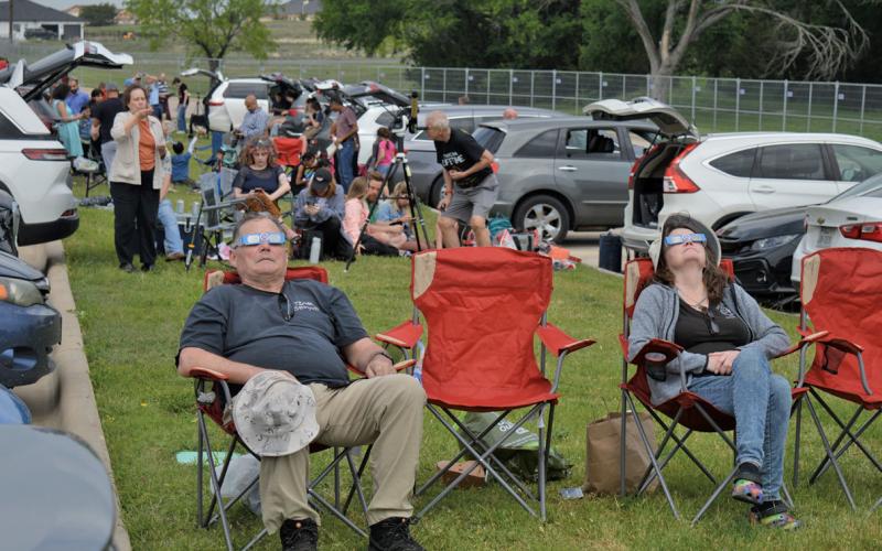 Eclipse chasers observe the solar event through their special viewing glasses during a partial phase before totality settled in here. ERICK MITCHELL | DISPATCH RECORD