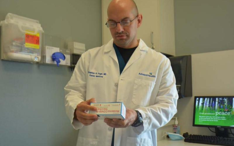 Dr. Stephen Vogel, a physician at AdventHealth Central Texas Family Medicine Clinic-Lampasas, handles a box of Moderna vaccines in his office Thursday. MONIQUE BRAND | DISPATCH RECORD