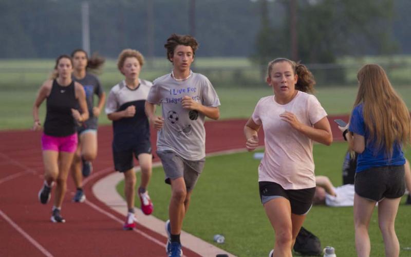 Tyler Ecker and Abby Valdez race around the track at Lampasas High School during cross country practice. HUNTER KING | DISPATCH RECORD