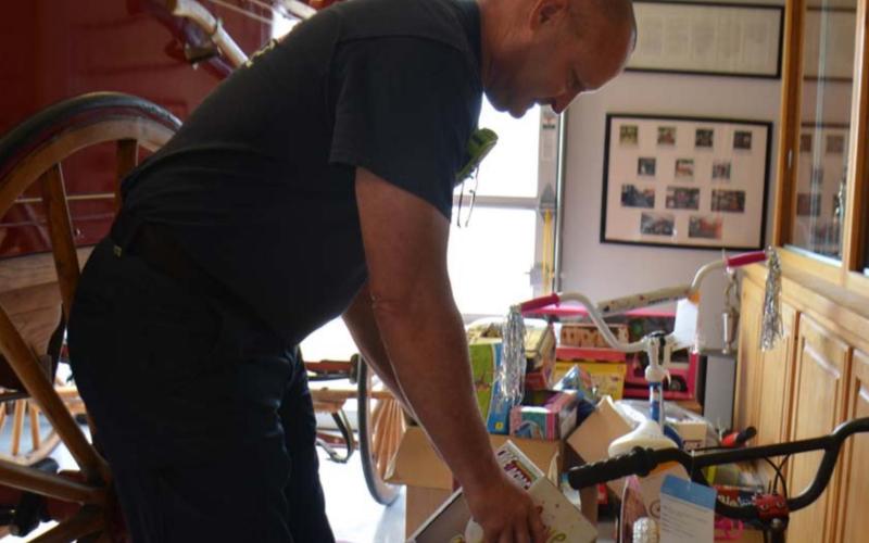 Lampasas firefighter Sean Schroeder sorts toys inside the fire station on Friday. Distribution to families that have applied will take place Dec. 18. Kempner residents may sign up for toys at the fire station there. Families in Lometa who would like to receive gifts should contact Lometa City Hall to participate in the toy drive. In Adamsville, area churches can assist families in need. MONIQUE BRAND | DISPATCH RECORD