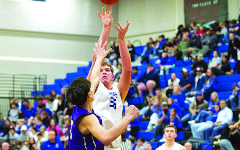 HUNTER KING | DISPATCH RECORD Beau Patterson shoots over an outstretched hand as the crowd watches behind him.