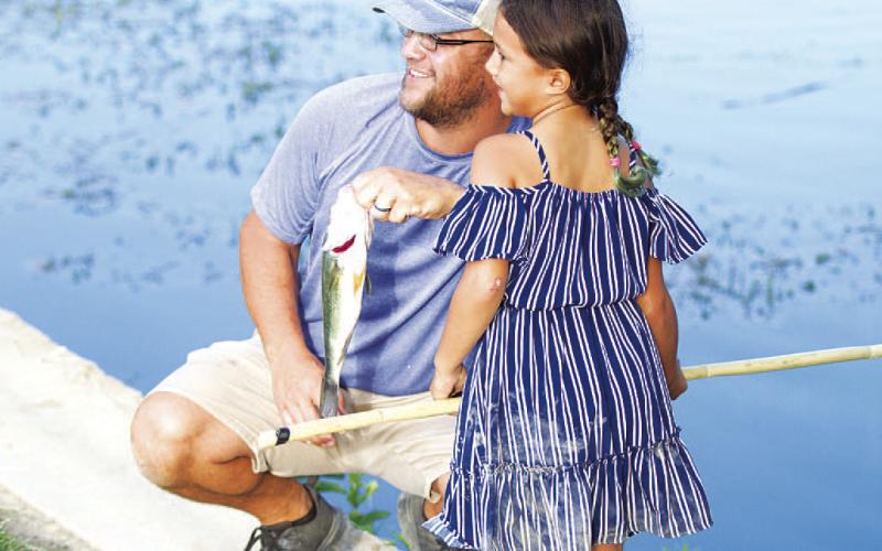 Jillian Rincones and her dad Nathan Rincones pose with her 13-inch bass at the fishing derby. HUNTER KING | DISPATCH RECORD