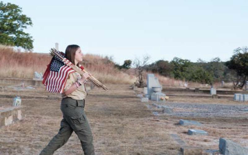 Braylie Eddinger marches into Oak Hill Cemetery with an armful of flags to place at the graves of military veterans. gabriela sangache | dispatch record