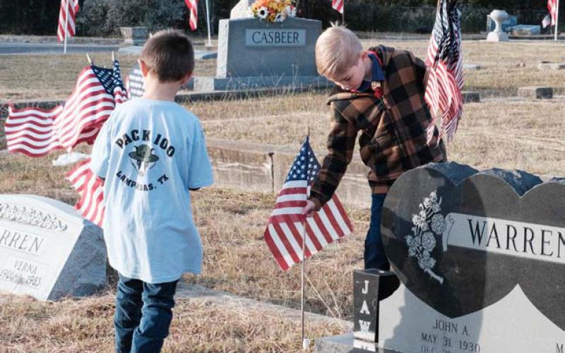 William Cross and Jaxson Carter, members of Lampasas Cub Scout Pack 100, place flags at a grave of a Lampasas veteran. gabriela sangache | dispatch record