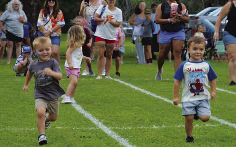 At left, Walker Cook and Theo Ray race to the finish line during last Friday’s Kids’ Day relay races. ERICK MITCHELL | DISPATCH RECORD