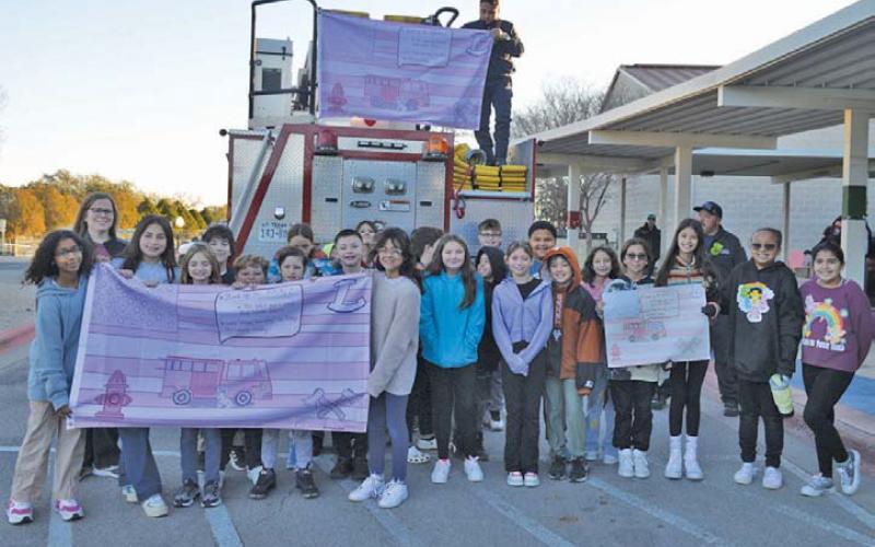 Erick mitchell | dispatch record Hanna Springs Elementary students in Mrs. White’s fifth-grade homeroom class stand in front of the Lampasas Fire Department engine as they hoist the winning flag on Tuesday morning.