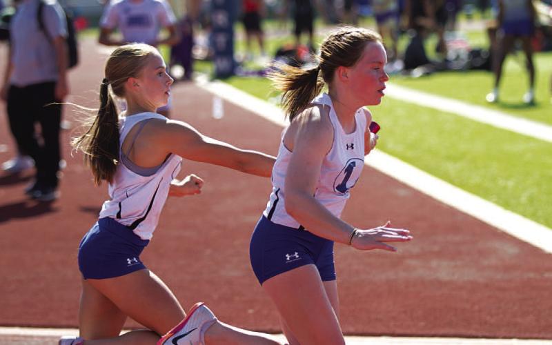 Aimee Weinheimer, left, passes the baton to Lola Patterson during the girls’ 4x100-meter relay. HUNTER KING | DISPATCH RECORD