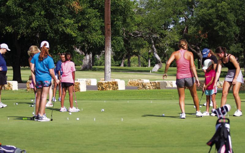 Some high school golfers worked with girls on their putting on the practice green. HUNTER KING | DISPATCH RECORD