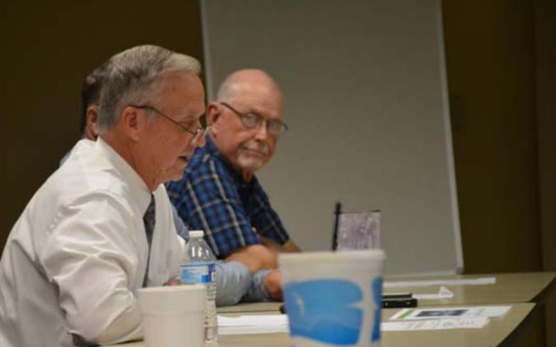 County Judge Randy Hoyer, left, reads the official motion before the Commissioners Court votes Tuesday evening, as Precinct 1 Commissioner Robert Carroll looks on. MONIQUE BRAND | DISPATCH RECORD