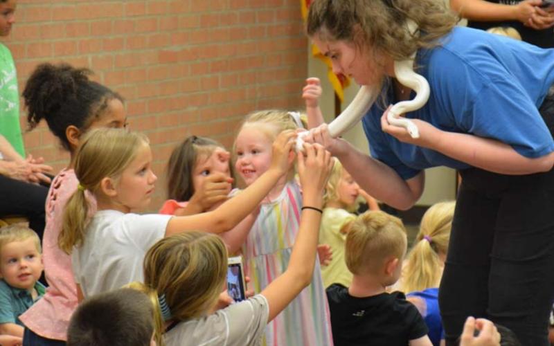 Lotus Blewett holds the Humane group’s leucistic snake as young library patrons have a chance to feel its scales. MASON HINES | DISPATCH RECORD