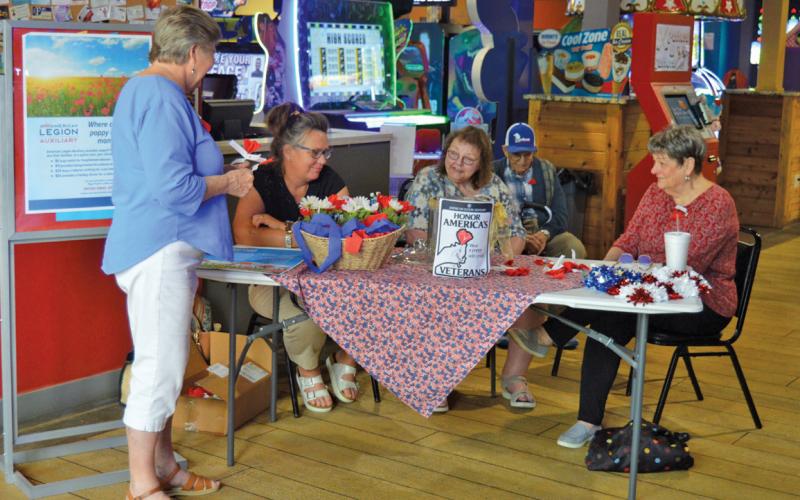 American Legion Auxiliary volunteers, left to right, Dorothy Hollister, Christiane Kielpinski, Ann Kielpinski and Jo Ann Cain prepare to hand out commemorative poppies to Putters &amp;amp; Gutters patrons to recognize National Poppy Day. Erick Mitchell| dispatch record
