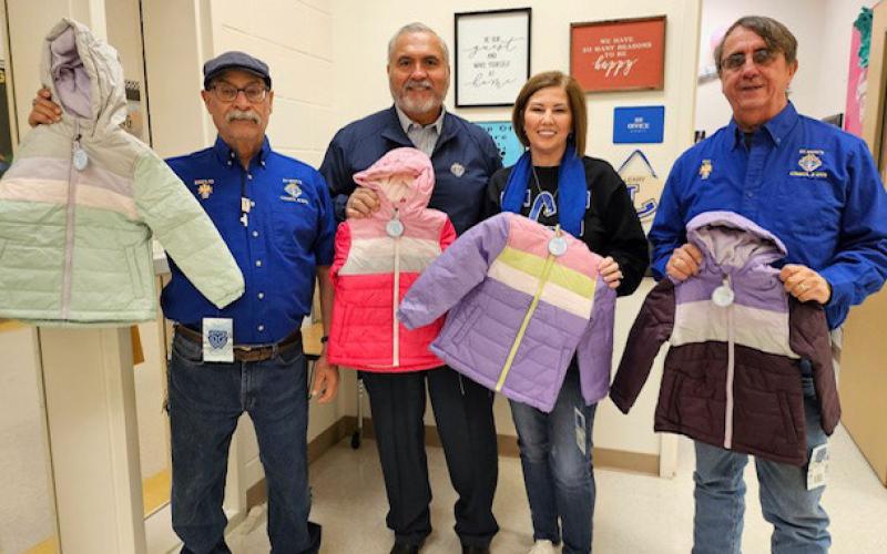 Knights of Columbus members Bacillio Zamanegio, Jess Ramos and Rey Medrano delivered jackets to Taylor Creek Elementary School earlier this month. Accepting the donation is teacher Michele Stivers. jim tracy | courtesy photo