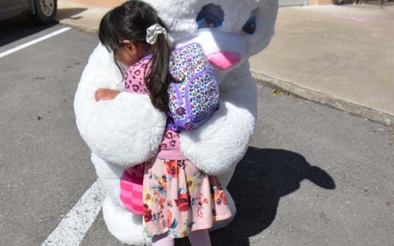 Two-year-old Lampasan Zaria Eva Ashley Rivera hugs the Easter Bunny tightly during the Aware Central Texas Easter kit drivethrough at the Lampasas Police Department headquarters. MONIQUE BRAND | DISPATCH RECORD
