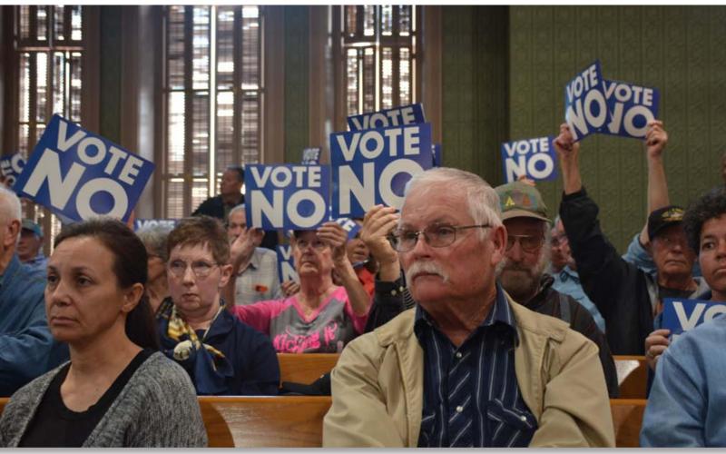 County residents hold up signs asking the Commissioners Court to vote “No” on a reinvestment zone for 3,800 acres of land where a solar farm could be constructed that would cover about 1,500 acres within the tract. MONIQUE BRAND | DISPATCH RECORD