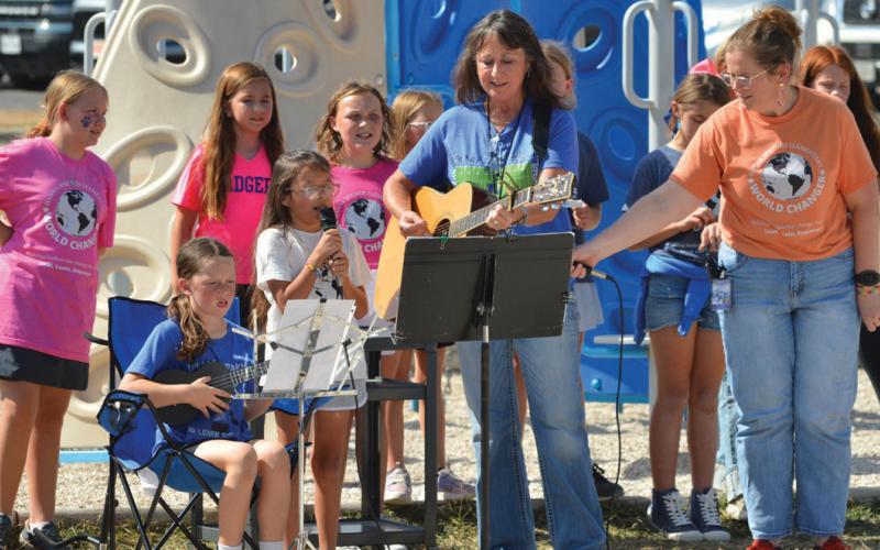 Hanna Springs Elementary School students Lacey Schreiber with the microphone and Hadlee Guthrie on the strings, with some help from teacher Loree Linehan, lead their classmates in the “Leader in Me” song during Friday’s pep rally. Erick Mitchell | Dispatch Record