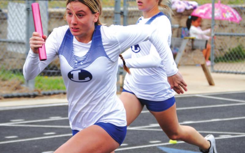 Cobie Chandler takes off with the baton during the girls’ 4x200-meter relay on Tuesday. Morgan Myers had just handed off the baton. HUNTER KING | DISPATCH RECORD