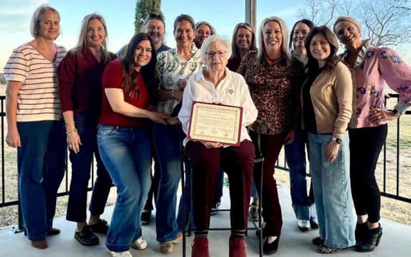 A group of Aggie Moms surrounds Carol Wright as she holds the club’s certificate recognizing its 35th anniversary. Wright was one of the founding members in 1990. COURTESY PHOTO