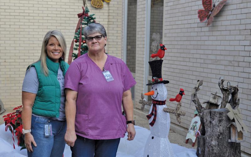 Erick mitchell | dispatch record Kline Whitis Elementary School Principal Leanne Bobo, at left, and custodian Mary Ejem stand In the life-size snow globe creation Ejem designed at the campus.