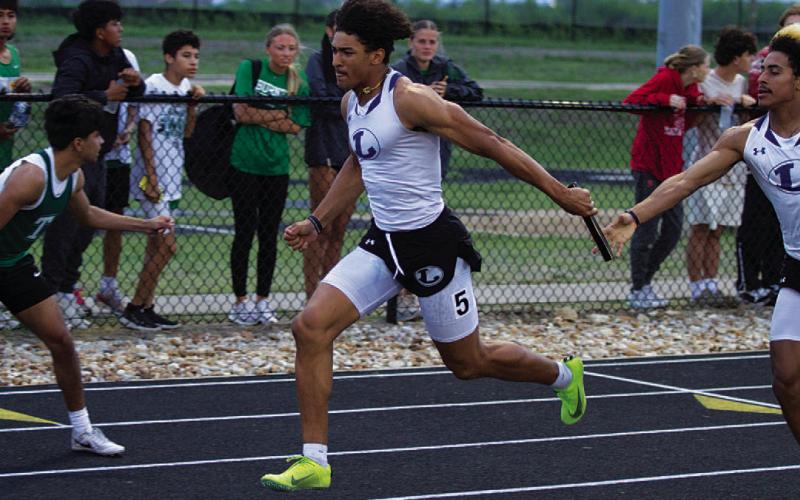 HUNTER KING | DISPATCH RECORD Ty Johnson receives the baton from Jaden McElwain during the 4x200-meter relay last Thursday.