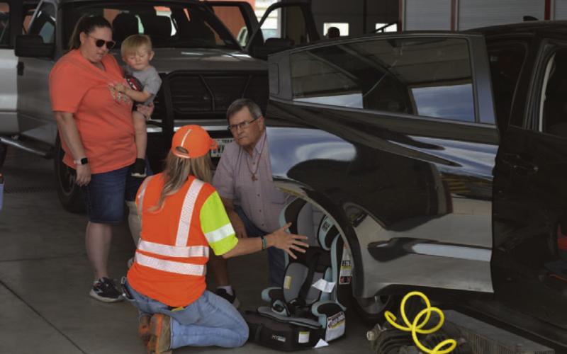 A Texas Department of Transportation-certified child passenger safety technician discusses the details of properly installing a child safety seat during lsat week’s child car seat check-up event. ERICK MITCHELL DISPATCH RECORD