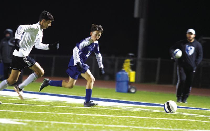 HUNTER KING | DISPATCH RECORD Kent Ashley runs to catch up to a ball on the left wing as head coach Samuel Burnside watches from the sideline.