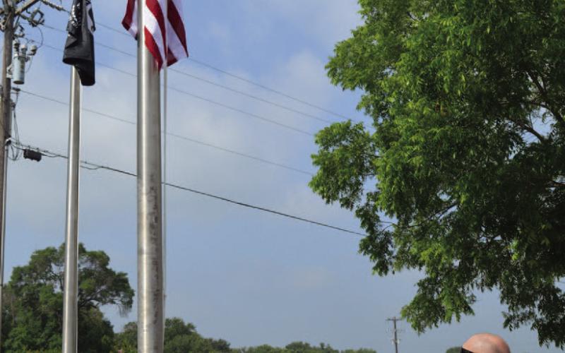 Those in attendance at Kempner’s Memorial Day ceremony pay their respect to the flag as Alicia Straley sings the national anthem. ERICK MITCHELL | DISPATCH RECORD