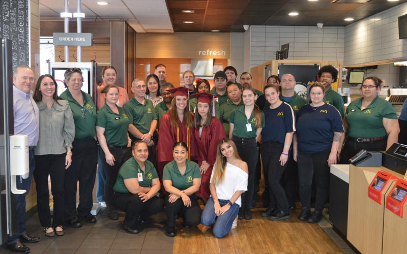 At center with their graduation gowns, Mary DeBellis and Maribel Rivera stand alongside the Lampaas McDonald’s team. Both DeBellis and Rivera received their college degrees through the McDonald’s Archways to Opportunity program. Erick Mitchell | dispatch record