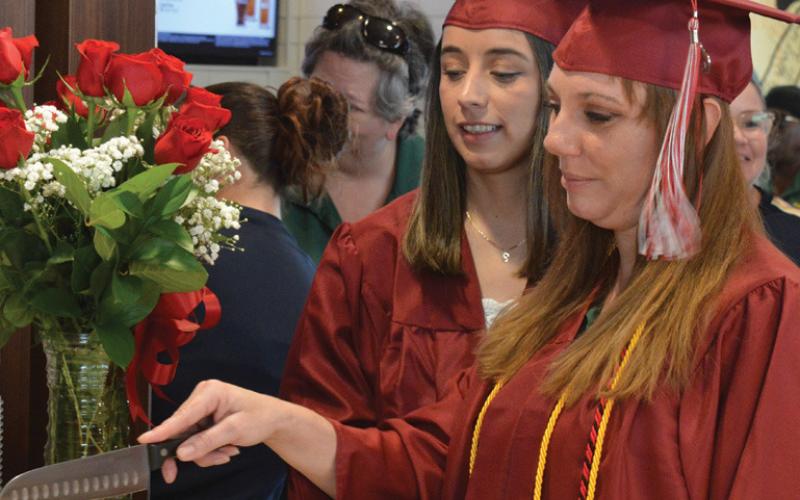 Erick Mitchell | dispatch record Mary DeBellis, on the right, cuts the celebratory graduation cake alongside Maribel Rivera at a special event Tuesday in their honor.