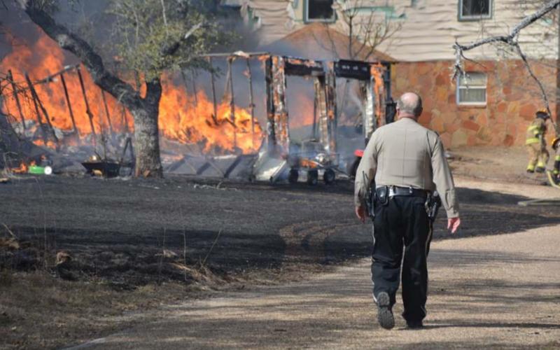 A deputy walks alongside County Road 1025 to aid other first responders at last week’s structure fire. MONIQUE BRAND | DISPATCH RECORD