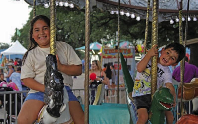 Ellie Flores and Palo Damron share smiles as they enjoy the carousel at the carnival. CHLOE COWDREY | DISPATCH RECORD