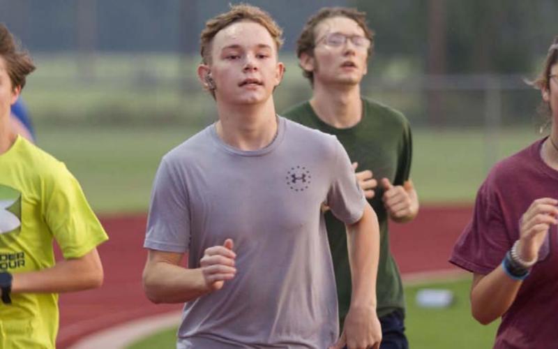 Colton Sheard, left, Jodiah Holland and Lilee Hamill run around the track during 600-meter exercises at cross country practice on Tuesday morning. HUNTER KING | DISPATCH RECORD