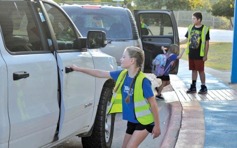 First-year World Changer McKaylynn McKinnon prepares to open the door for a fellow student during morning drop-off patrol. erick mitchell | dispatch record