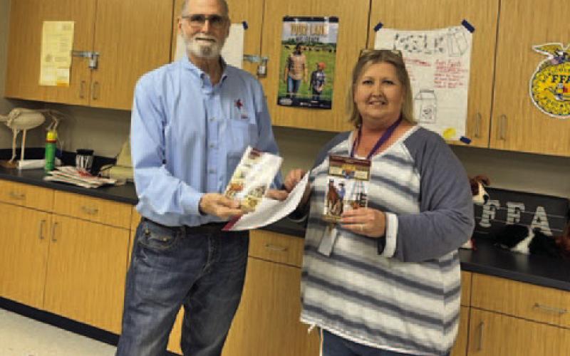 Farm Bureau representative Steve Forsythe presents the donation of John Erickson’s “Hank the Cowdog Ranch Life” books to Lampasas High School teacher Judy Hail. COURTESY PHOTO