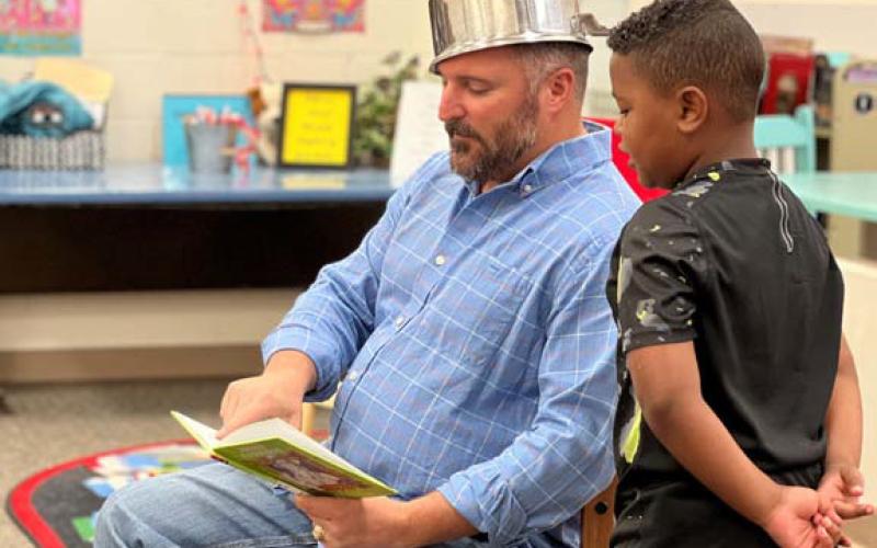 Lampasas ISD school board member Jeff Rutland, decked out as Johnny Appleseed, reads a book alongside first-grader Eli Vazquez on Monday. court esy photo