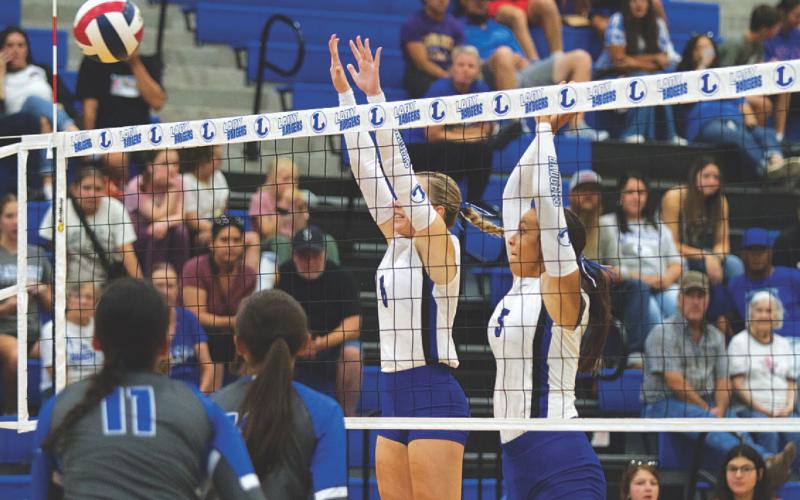 HUNTER KING | DISPATCH RECORD Scout Barton, left, and Madison Magilke leap for a block at the volleyball team’s home opener.